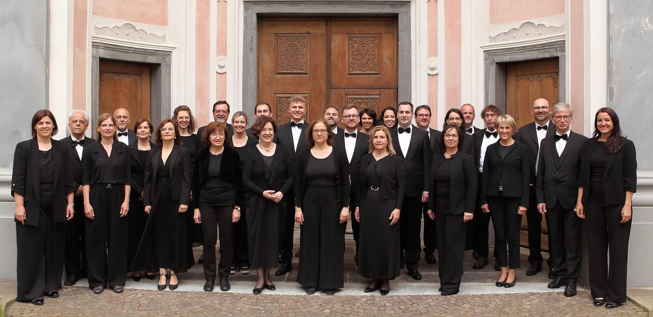 Gruppenfoto der Sängerinnen und Sänger des MGV Bozen vor einem Kirchenportal