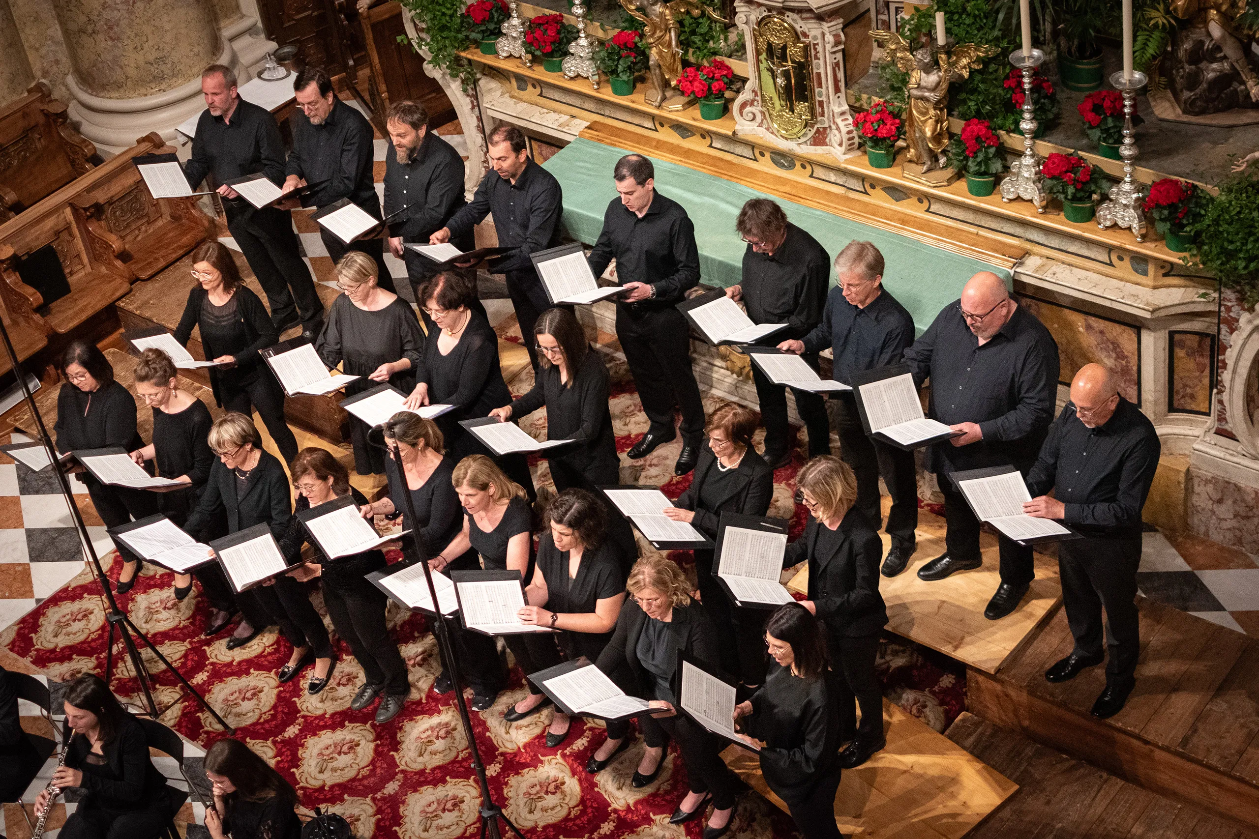 Sängerinnen und Sänger des MGV Bozen mit Notenmappen im Altarraum einer Kirche